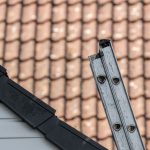 a metal extension ladder on a roof. Learn how to safely raise and lower an extension ladder with Matthews' Painting Company.