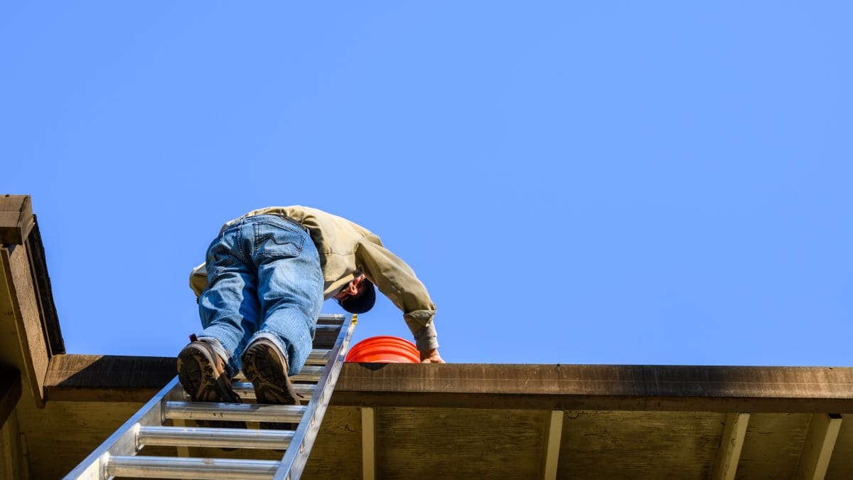 An elderly man climbs a ladder to his roof. Matthews' Painting Company's Stay Off the Ladder service project helps prevent falls and injuries for senior citizens and disabled veterans.