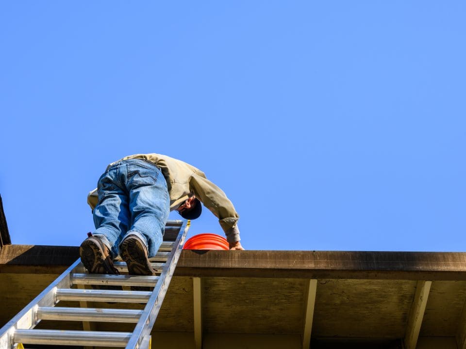 An elderly man climbs a ladder to his roof. Matthews' Painting Company's Stay Off the Ladder service project helps prevent falls and injuries for senior citizens and disabled veterans.