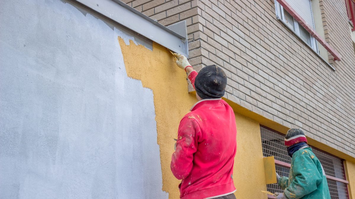 Builder workers plastering exterior wall
