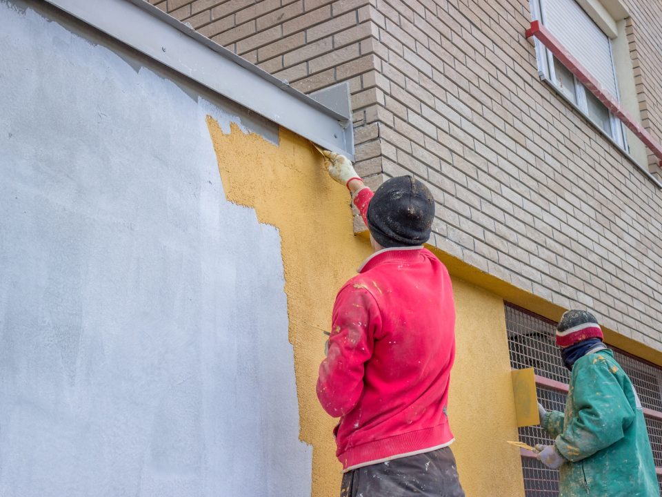 Builder workers plastering exterior wall