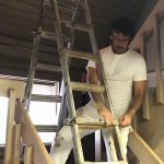 Professional painter safely setting up an adjustable ladder on a stairway for interior painting.